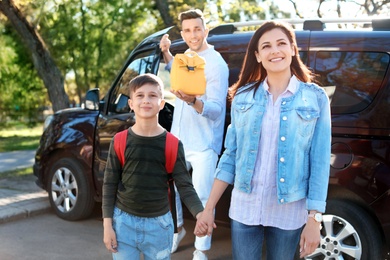 Young man reminding his little child to take lunch bag as he leaving for school