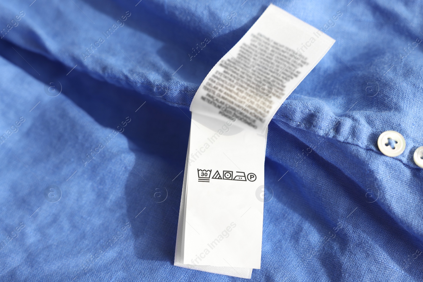 Photo of Clothing label in different languages on blue garment, closeup