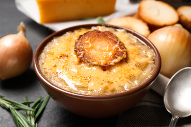 Tasty homemade french onion soup served on black table, closeup