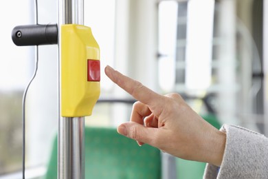 Photo of Woman pressing stop button in public transport, closeup