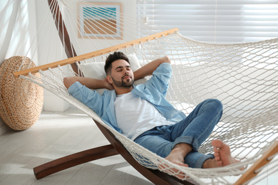 Photo of Young man relaxing in hammock at home