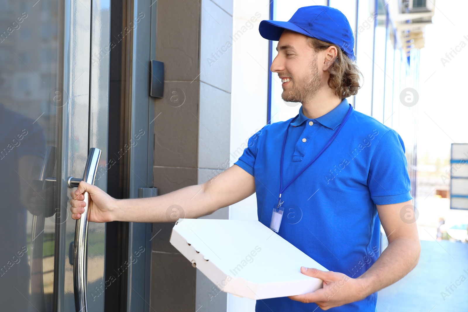 Photo of Male courier with pizza at entrance. Food delivery service