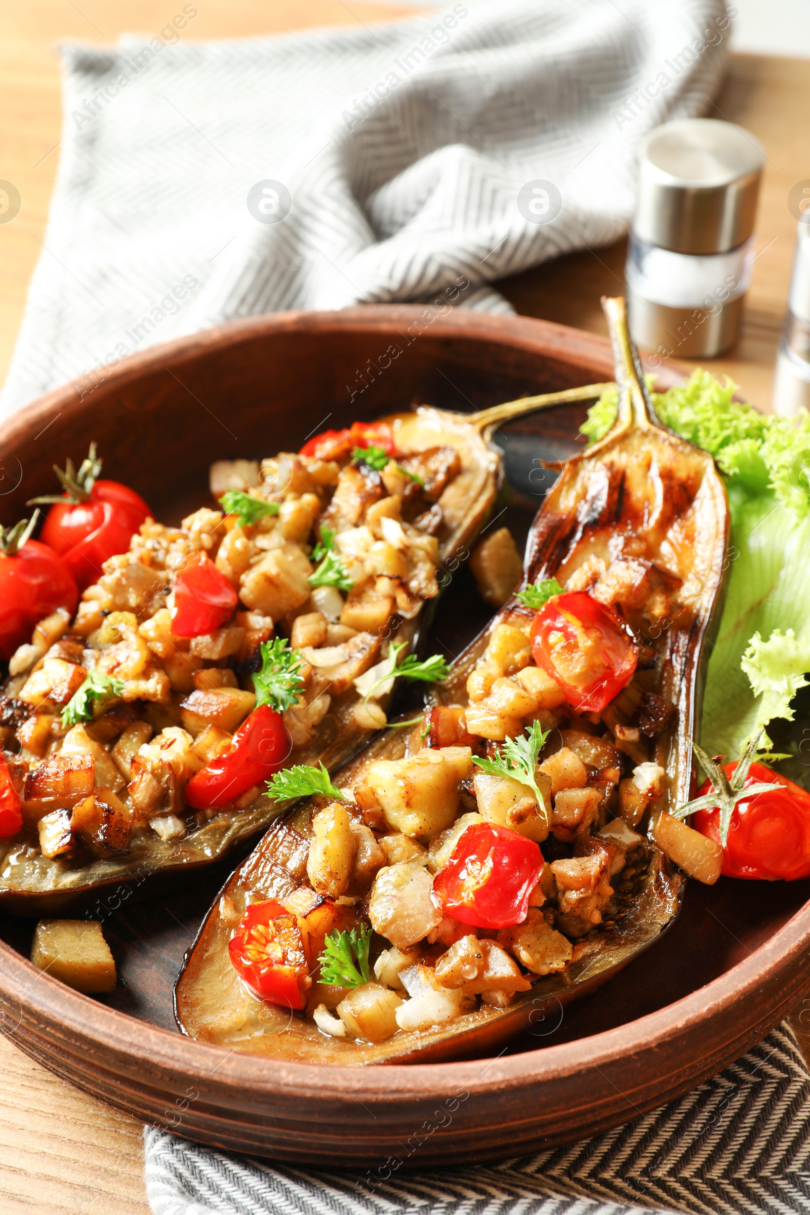 Photo of Bowl with tasty stuffed eggplants on wooden table, closeup