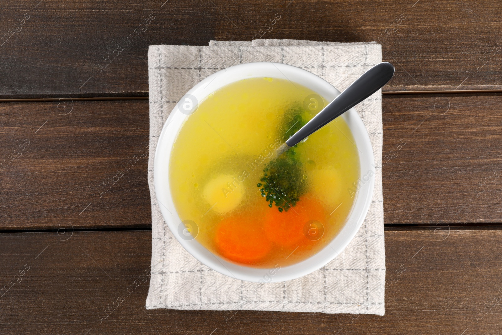 Photo of Tasty soup with vegetables in bowl served on wooden table, top view