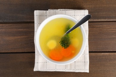 Tasty soup with vegetables in bowl served on wooden table, top view