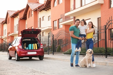 Photo of Happy family with their dog near car on street