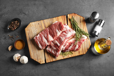 Photo of Raw ribs with herbs and spices on grey table, flat lay