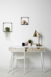 Photo of Comfortable workplace with white desk near wall indoors