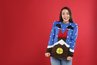 Young woman in Christmas sweater on red background, space for text