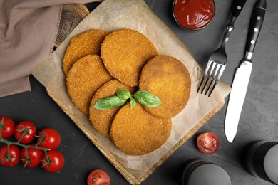 Delicious fried breaded cutlets served on black table, flat lay
