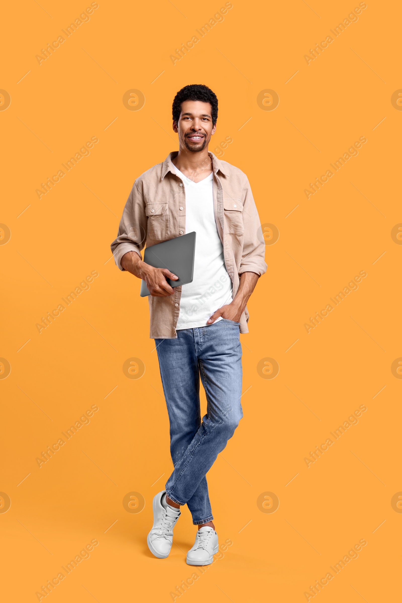 Photo of Happy man with laptop on orange background