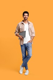 Photo of Happy man with laptop on orange background