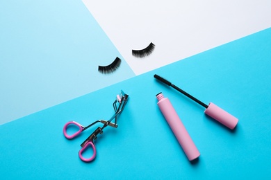 Photo of False eyelashes, curler and mascara on color background, flat lay