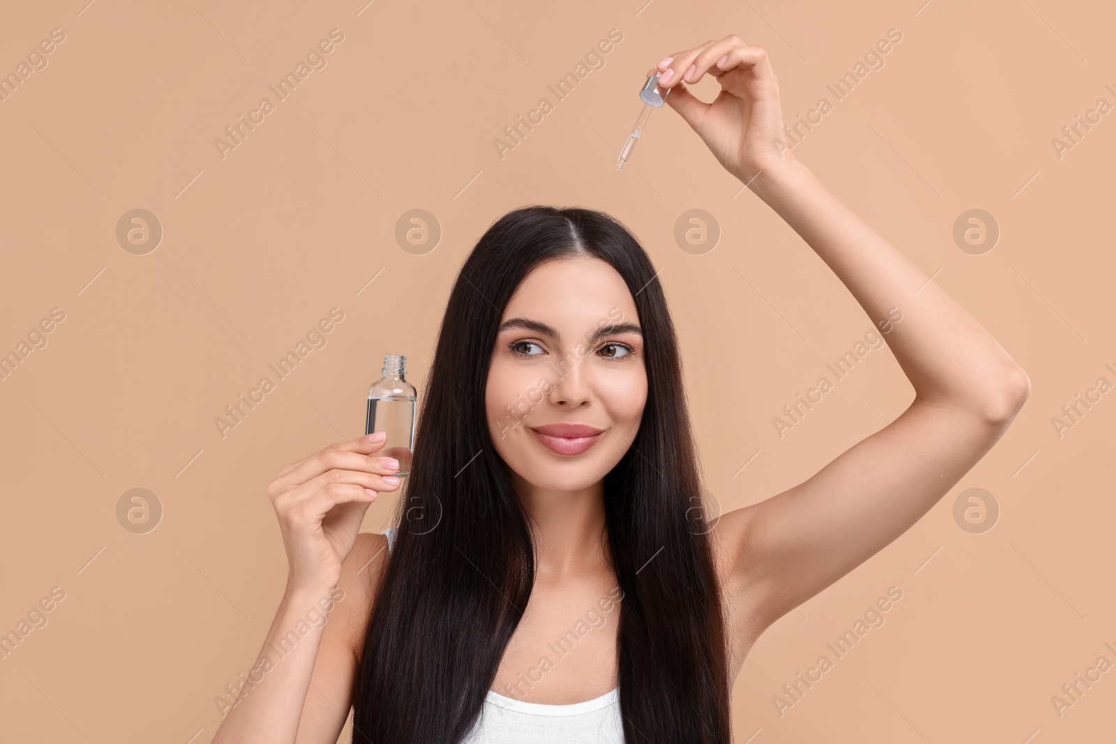 Photo of Beautiful woman applying hair serum on beige background. Cosmetic product