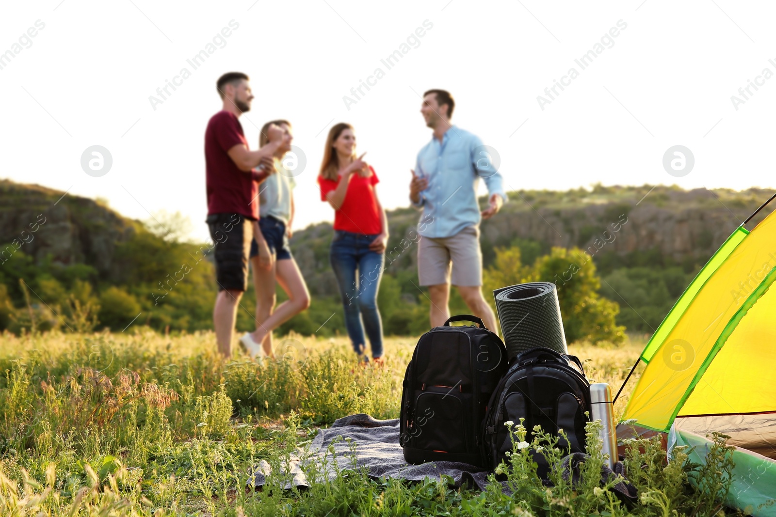 Photo of Camping gear and group of young people in wilderness