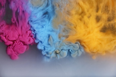 Photo of Splash of pink, light blue and yellow inks on grey background