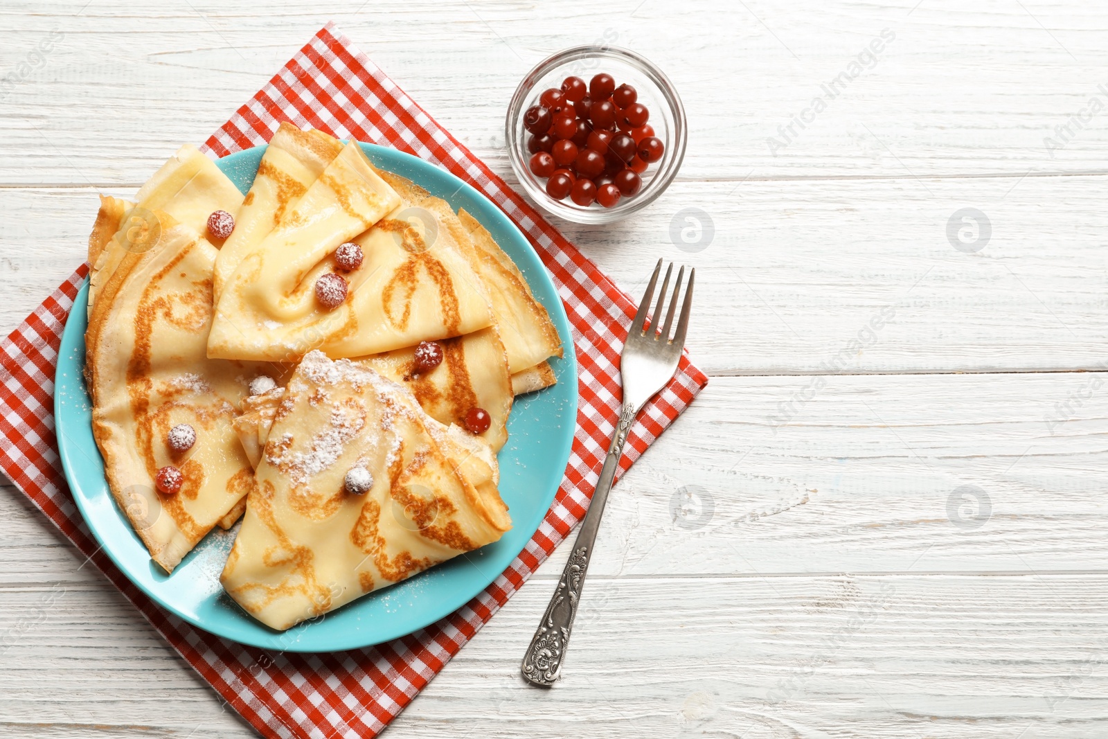 Photo of Thin pancakes served with sugar powder and berries on plate, top view