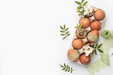 Flat lay composition with Easter eggs, twigs and lace ribbon on white background. Space for text