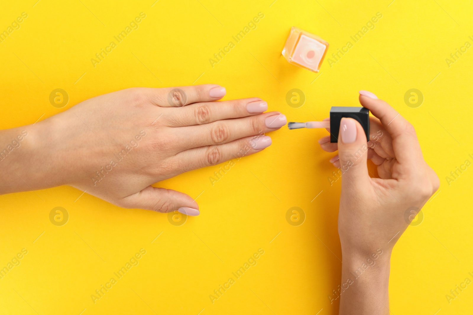 Photo of Woman applying nail polish on color background, above view