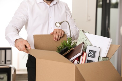 Photo of Young man with box of stuff in office, closeup