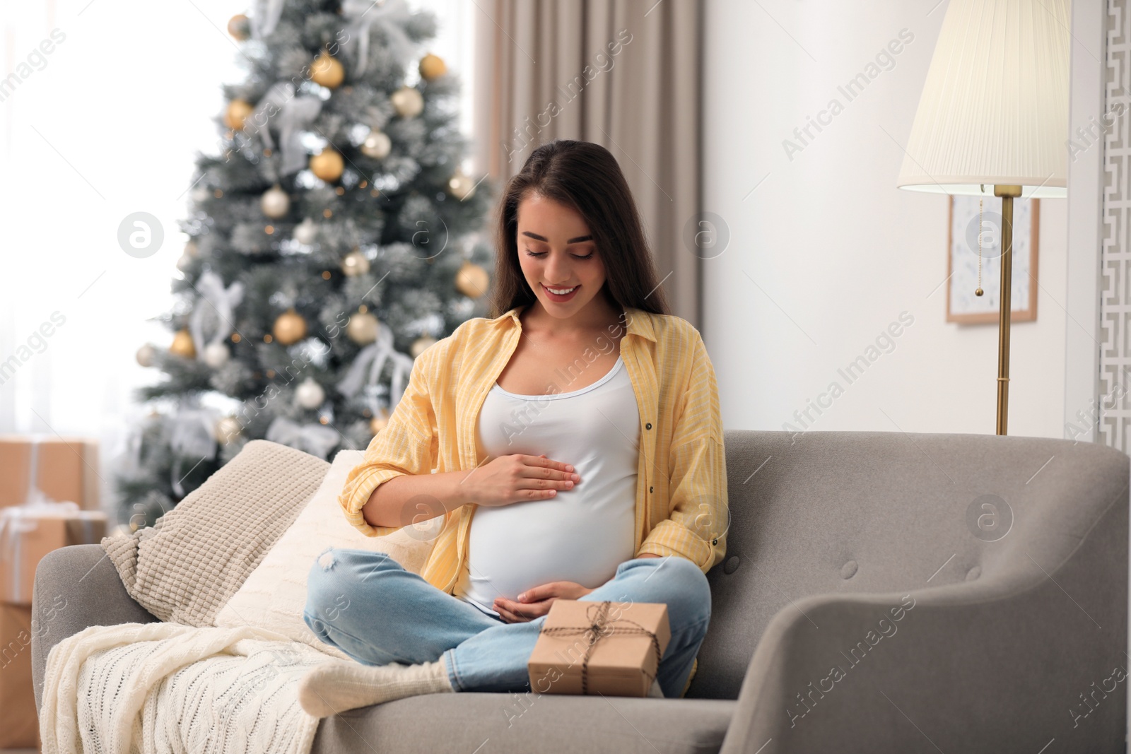 Photo of Happy pregnant woman with Christmas gift box at home. Expecting baby