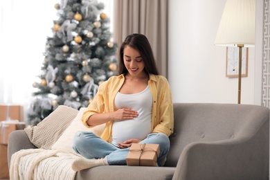 Photo of Happy pregnant woman with Christmas gift box at home. Expecting baby