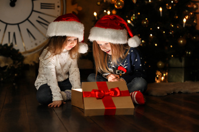 Photo of Cute children opening magic gift box near Christmas tree at night