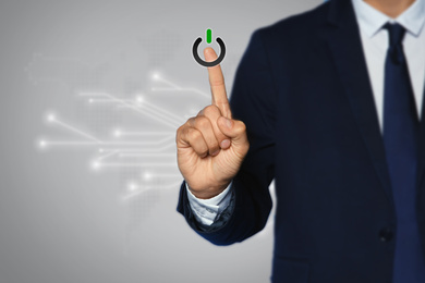 Man pressing power button on virtual screen, closeup 