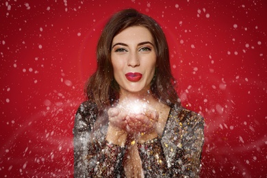Beautiful woman blowing glitter on red background. Christmas party