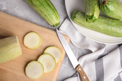 Photo of Wooden board with fresh ripe zucchini and knife on grey background, flat lay