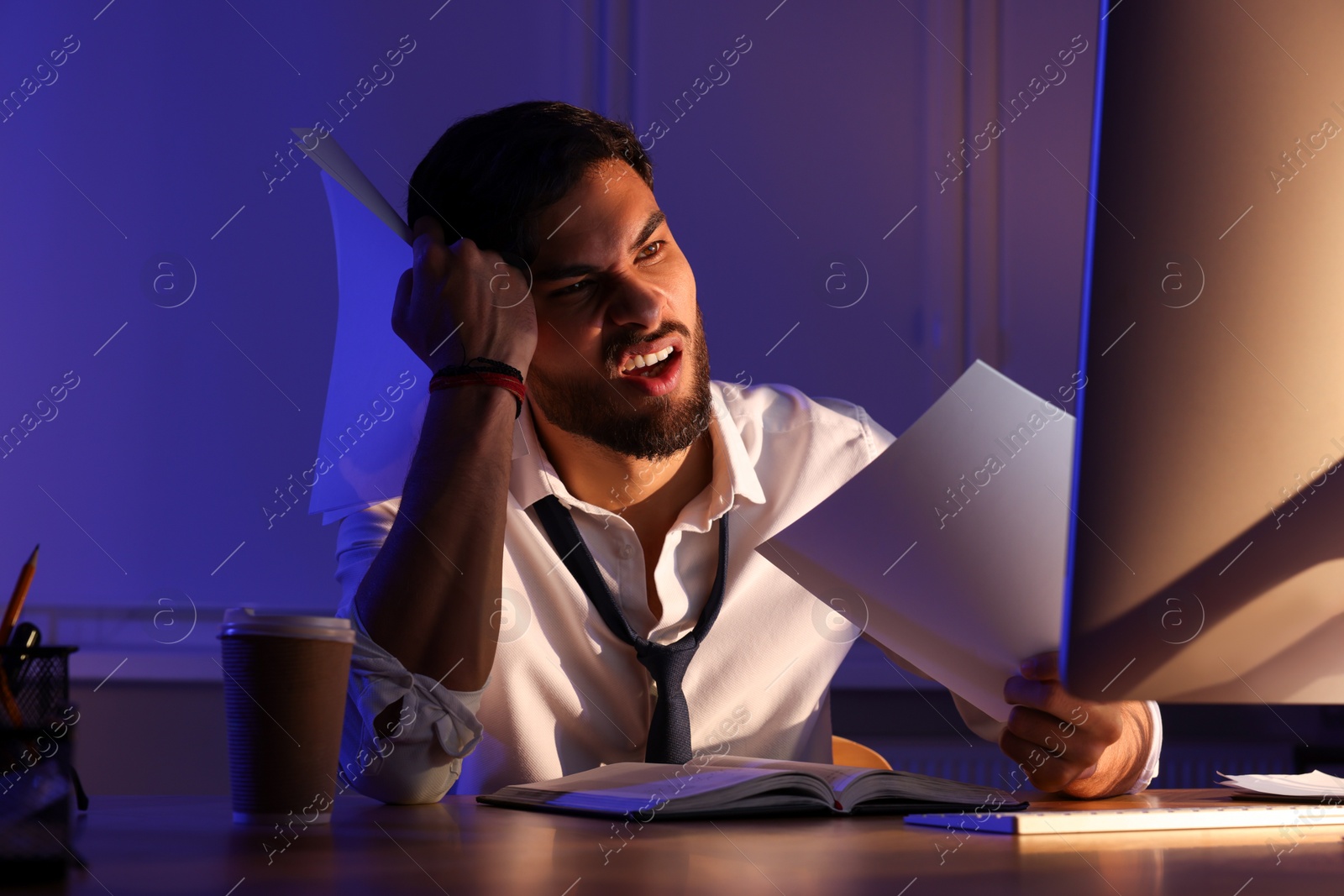 Photo of Tired young man working late in office