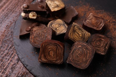 Different tasty chocolate candies on slate plate