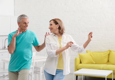 Photo of Happy senior couple dancing in kitchen at home