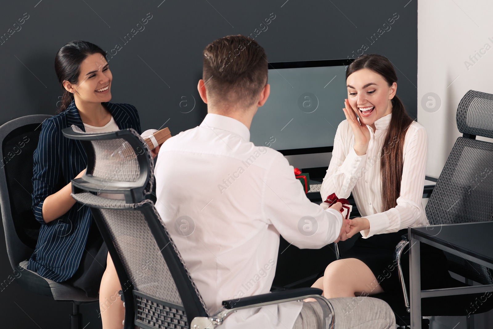 Photo of Colleagues presenting gifts each other in office