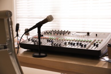 Microphone and professional mixing console on wooden table in radio studio