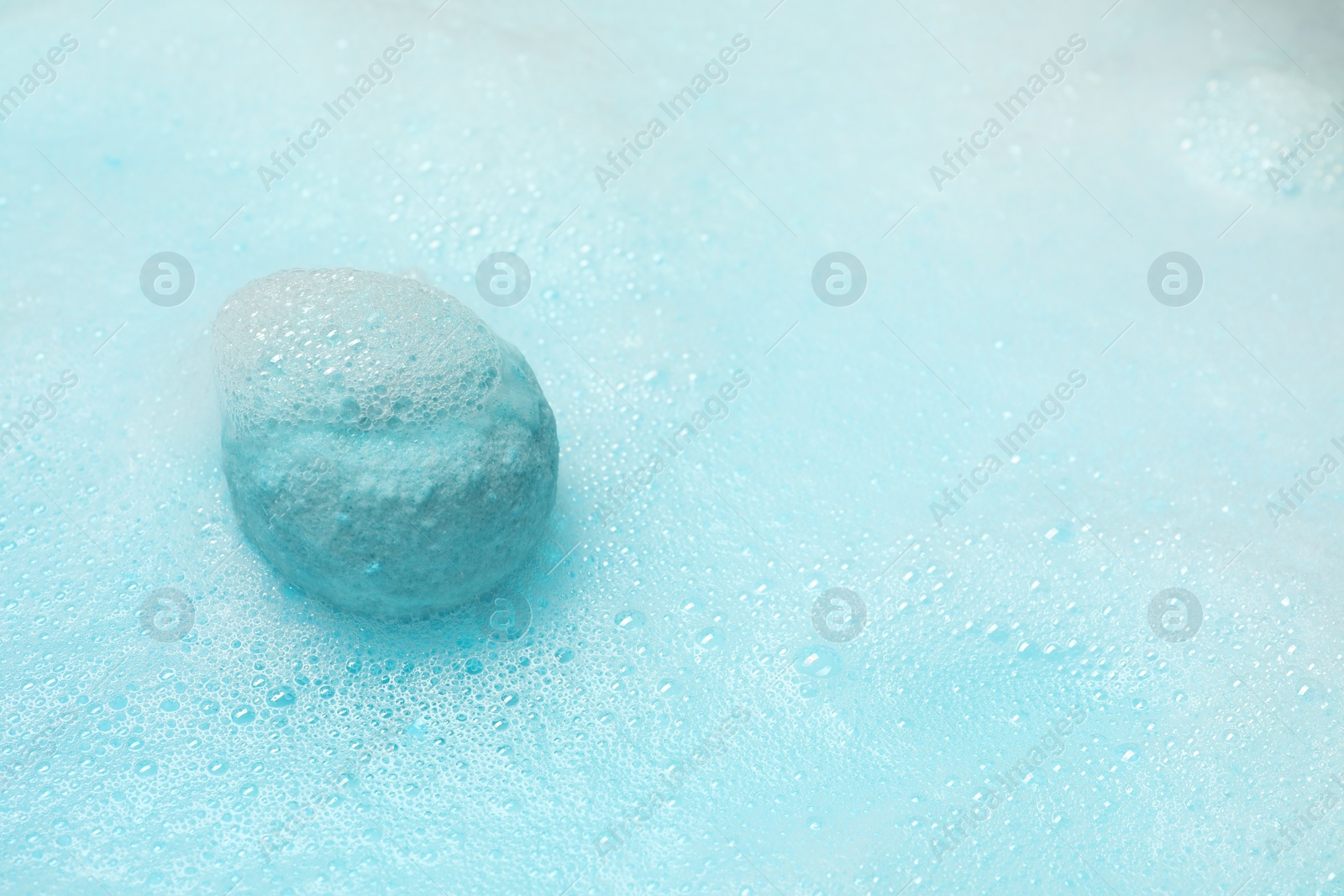 Photo of Light blue bath bomb dissolving in water. Space for text