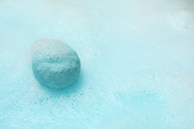 Light blue bath bomb dissolving in water. Space for text