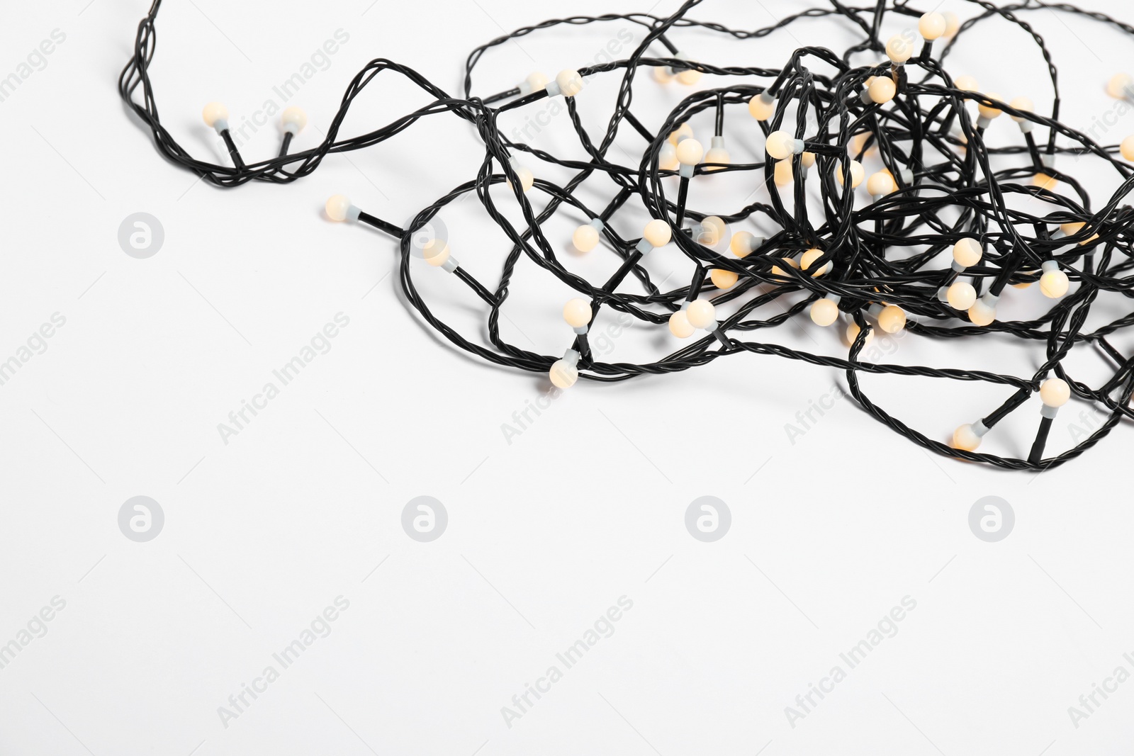 Photo of Tangled strings of Christmas lights on white background