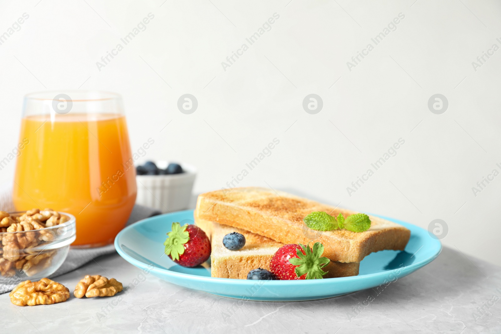 Photo of Delicious breakfast with toasted bread and berries on light grey marble table against white background