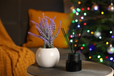 Photo of Aromatic reed air freshener and lavender on side table in cozy room