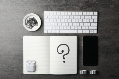 Photo of Notebook with question mark, smartphone and keyboard on grey table, flat lay