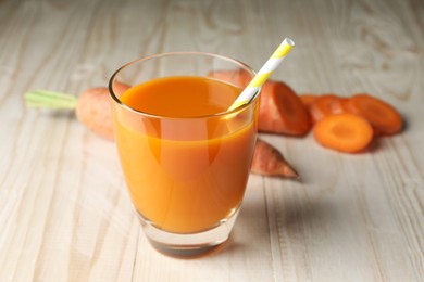 Photo of Glass of tasty carrot juice on wooden table, closeup