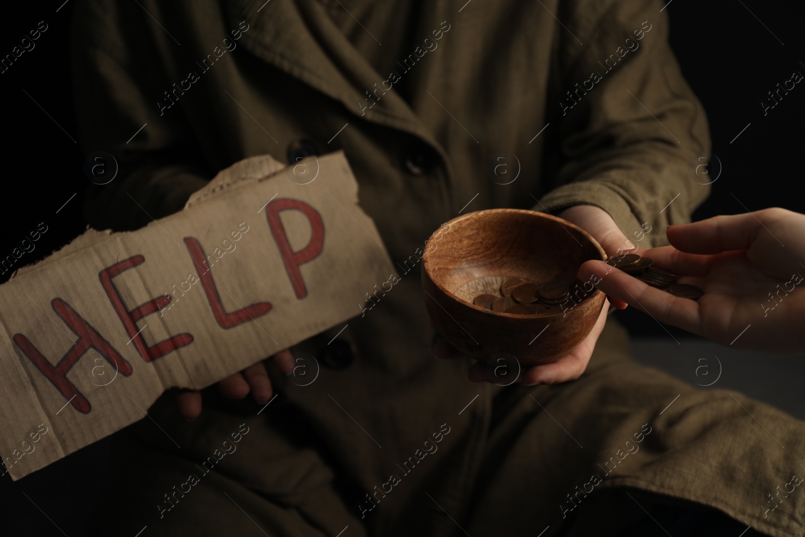 Photo of Woman giving coins to homeless with help sign, closeup. Charity and donation