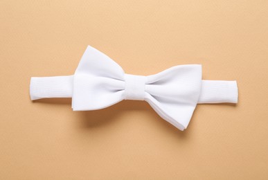 Photo of Stylish white bow tie on beige background, top view