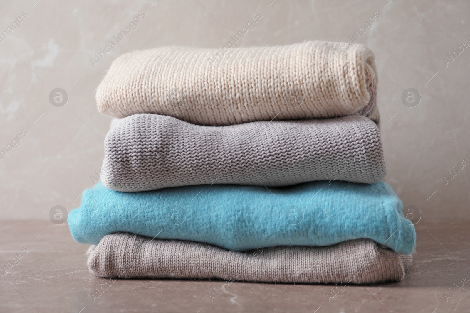 Photo of Stack of warm knitted clothes on table