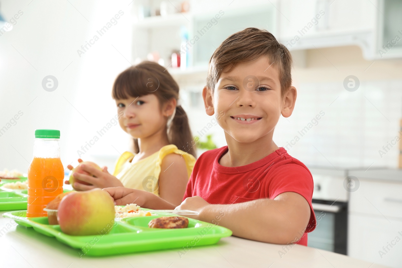 Photo of Children sitting at table and eating healthy food during break at school