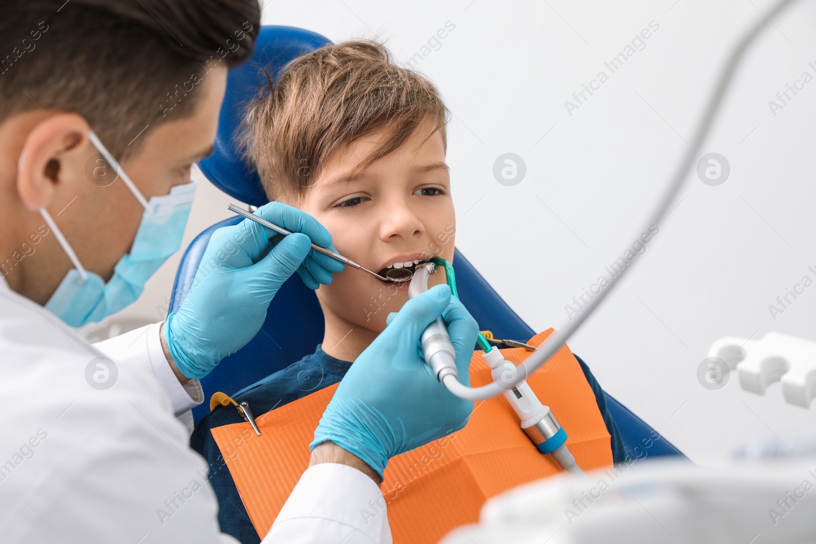 Photo of Professional dentist working with little boy in clinic