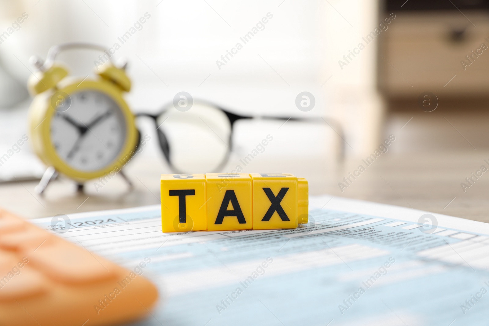 Photo of Yellow cubes with word Tax and documents on table, selective focus