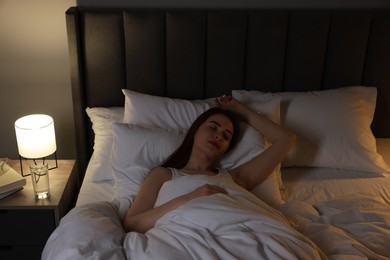 Photo of Beautiful young woman sleeping in bed at night