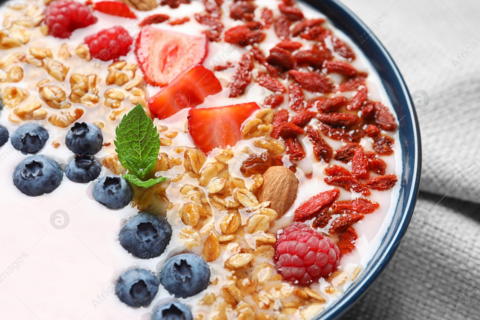 Photo of Smoothie bowl with goji berries on grey fabric, closeup
